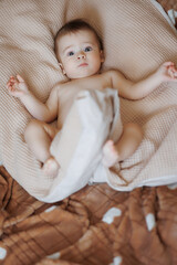 A baby is laying on a bed with a blanket. The baby is looking at the camera