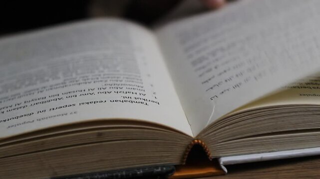 close up of unknown man's hand turning the pages of a book