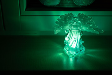 Plastic glowing figure of an angel with wings by the window.
