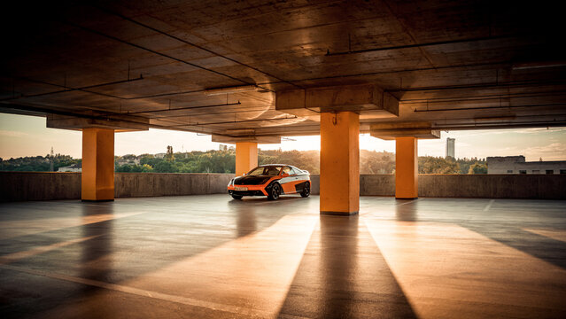 Orange car in parking garage at sunset. Toyota Celica parked in empty parking garage. Low setting sun shines parallel to the ground floor. Kyiv, Ukraine - June 09 2014.