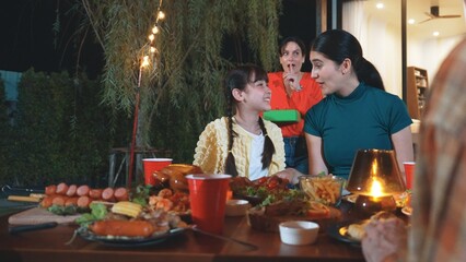 Family together celebrate holiday. Senior try to surprise granddaughter by quietly give gift. Outdoor activity to relax with relative, spend time with multigeneration cross generation gap. Divergence.