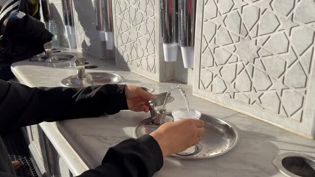 Pilgrim girl drinks zamzam water in the Prophet's Mosque in Medina Saudi Arabia.