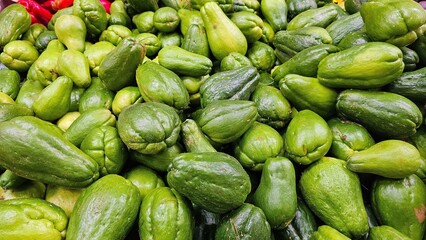 Close-up photo of raw green chayote being sold at a traditional market