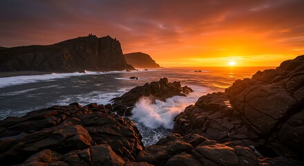 Obraz premium A rocky coastline with waves crashing against the cliffs under a vibrant orange sunset