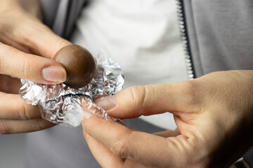 Female hands unwrapping a chocolate candy. Candy in a wrapper close-up. Copy Space