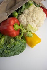 Vegetables lie on a white table. Grocery shopping. Food products close-up. Shopping bag top view. Copy space