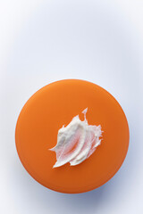 Jar cream on white background. Cosmetics close-up. Orange lid on table. Skin care. Beauty and spa. Copy space