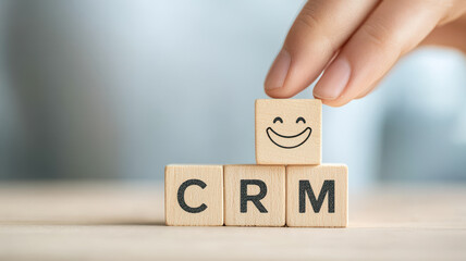 Wooden blocks spelling CRM with hand adding smiling block, symbolizing positive customer relationship management. creative and engaging representation of business success