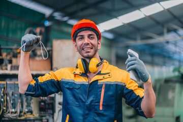 Skilled Worker in Industrial Workshop Poses Confidently With Tools in Hand