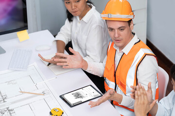 Diverse group of civil engineer and client working together on architectural project, reviewing construction plan and building blueprint at meeting table. Prudent