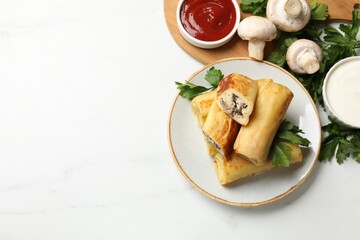 Delicious rolled crepes with mushrooms, parsley, ketchup and sour cream on white marble table, flat lay. Space for text