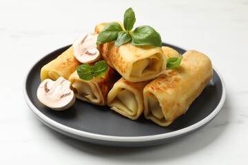 Delicious rolled crepes with mushrooms and basil on white marble table, closeup