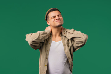 Tired young man feeling pain in neck joint, massaging muscles, rubbing head.