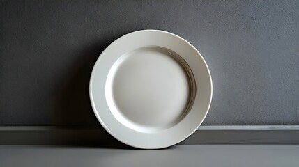 A white plate is sitting on a grey wall