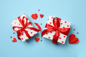 Gift boxes with red hearts on color  background