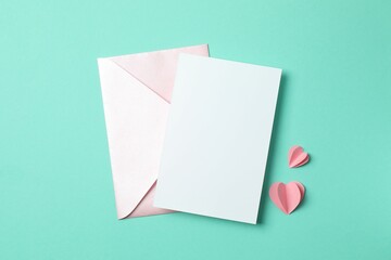 Paper card with envelope and red heart on color background