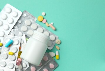 Various pills with medicine bottle on color background
