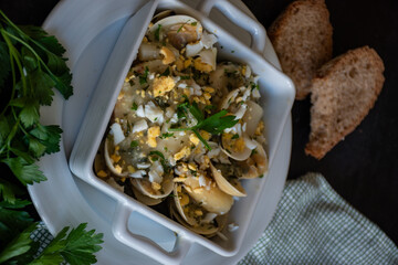 merluza vasca. fish dish. elegantly presented in a white casserole dish. traditional spanish recipe. merluza a la vasca.