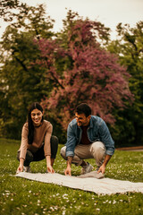 Loving couple spreading a blanket and getting ready to have a beautiful picnic day