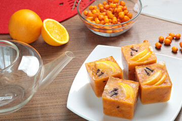 Tea made from frozen briquettes of sea buckthorn, orange and spices in teapot in kitchen. Healthy eating and seasons. Quick beverages to make.