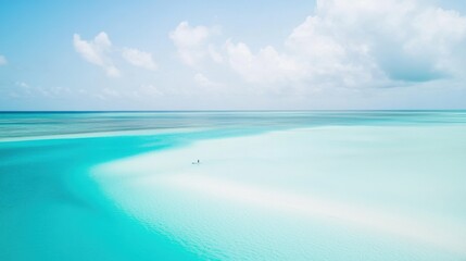 Fototapeta premium Endless turquoise waters stretch to the horizon, blending seamlessly with a clear blue sky, as two paddleboarders glide across the calm, shallow lagoon, embodying ultimate serenity.