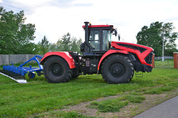 a red tractor with a black wheel with a plow on the side