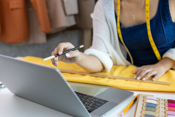 A woman who is running an online clothing business and is also a designer, working on designing...