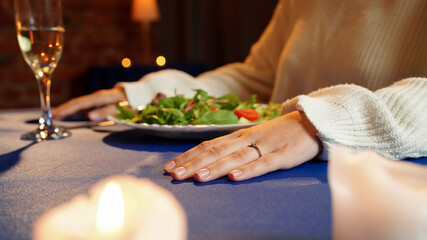 Couple celebrating valentines day and having a romantic dinner in restaurant, sitting at table enjoying evening, close up of woman hand with wedding ring.