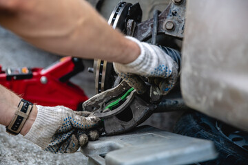 Mechanic man installing new brake disc and brake pads on car, car repair