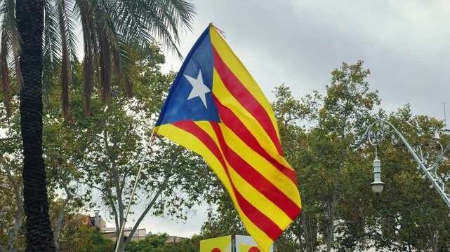 Catalonia independence flag on blue sky. Demonstration on Spanish National day advocating for Catalonia independence. High quality 4k footage