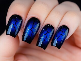 A woman's hand holding a blue and black manicure with a crackle design on it