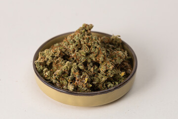 in a bowl dry flowers of medical cannabis. On a light background
