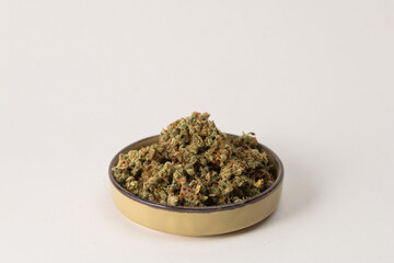 in a bowl dry flowers of medical cannabis. On a light background