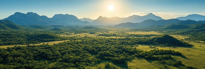 Fototapeta premium A breathtaking panoramic view showcasing a lush, expansive valley with rolling hills and towering mountains under a golden sunrise, illustrating the stunning beauty of untouched natural landscapes