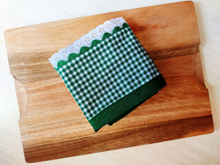 Folded green cloth napkin on the wooden cutting board with copy space. Barbecue, breakfast and meal concept.	