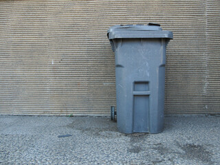 An old gray trash bin put on the house's terrace is used to dispose of rubbish.