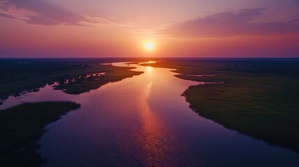 Fototapeta premium Aerial view of the serene Okavango river at sunset, capturing the tranquil beauty of the landscape. The vibrant colors create a stunning scene, offering ample photo style copy space.