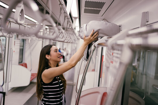 Young female tourist placing her luggage on the shelf inside a subway train, preparing for an exciting journey through the city while enjoying the convenience of public transport
