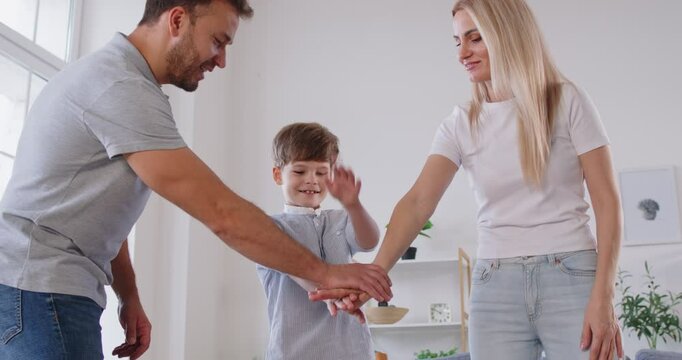 Family with a son stands in a circle at home, holding hands and embracing each other. Bond and teamwork within the family, showcasing love, togetherness, collaboration and happiness together.