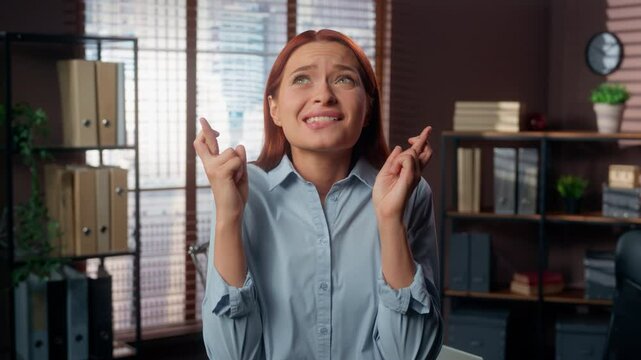 Hopeful Caucasian business woman girl female businesswoman employer company worker in office close eyes crossed fingers hope wish superstitious gesture wishing luck want to win waiting good news pray