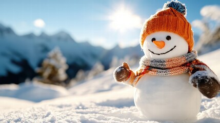 Obraz premium A smiling snowman, donning an orange hat and scarf, stands happily in the sunshine. Snowy mountains form a stunning backdrop with a clear blue sky.
