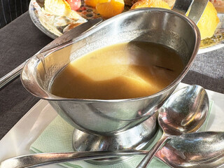 Delicious gravy in a silver sauce boat on a dining table