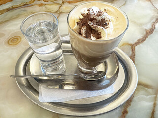 Iced coffee with whipped cream and chocolate shavings on marble table