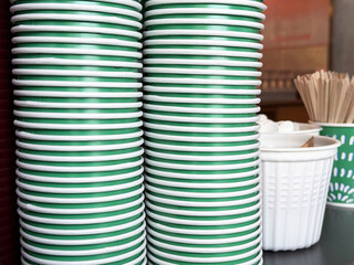 Stacked green and white paper cups with coffee stirrers in a cafe setting