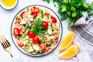 Middle Eastern salad with bulgur, tomatoes, cucumbers and parsley.. White background, top view