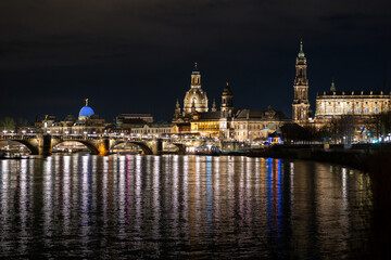 Obraz premium Dresden, Germany old town during the evening. Illuminated buildings next to the Elbe river. Beautiful cityscape with landmarks like the Frauenkirche and the Augustusbrücke.