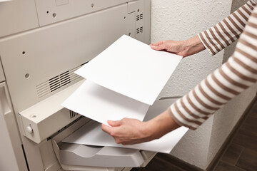 Woman using modern printer indoors, closeup. Printing house