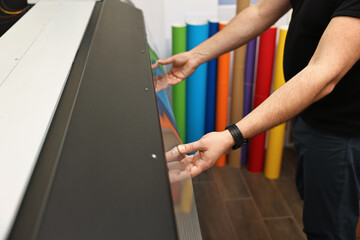 Man using wide-format printer indoors, closeup. Printing house