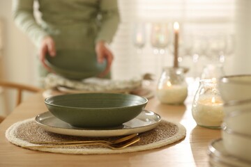 Woman setting table for dinner at home, closeup