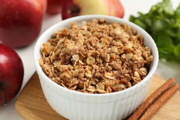Delicious apple crisp in bowl, cinnamon, fresh fruits and mint on table, closeup